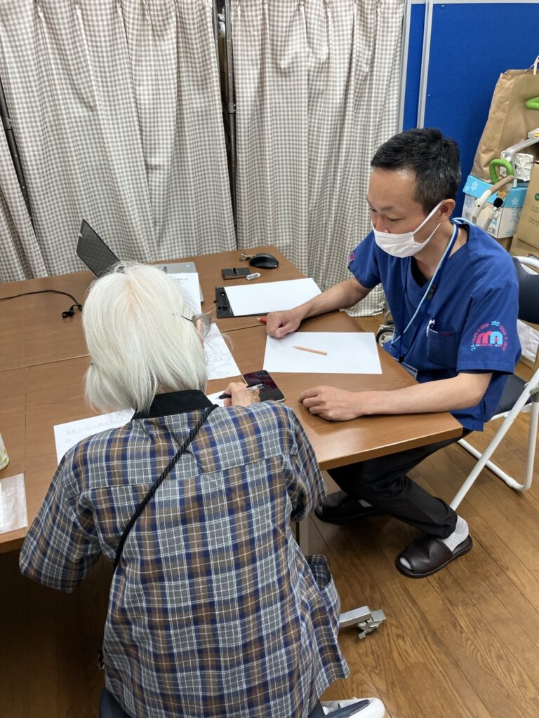 めぐみの会 大泉の相談室で、職員がシニアの方にスマホの使い方を説明する様子